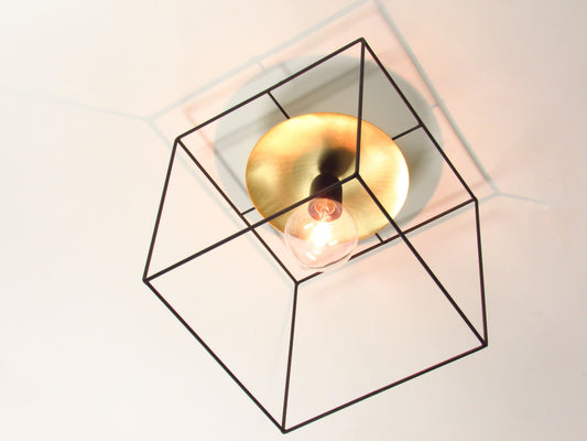 Modern ceiling light fixture with a black cubic frame and gold center disc