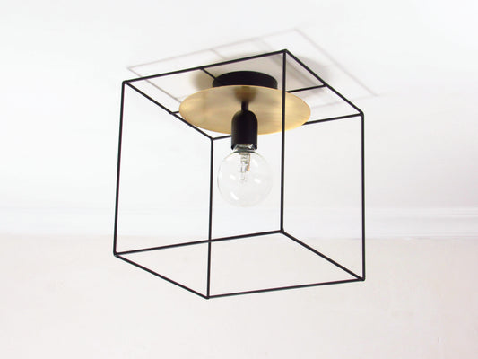 Modern ceiling light fixture with a black cubic frame and gold center disc