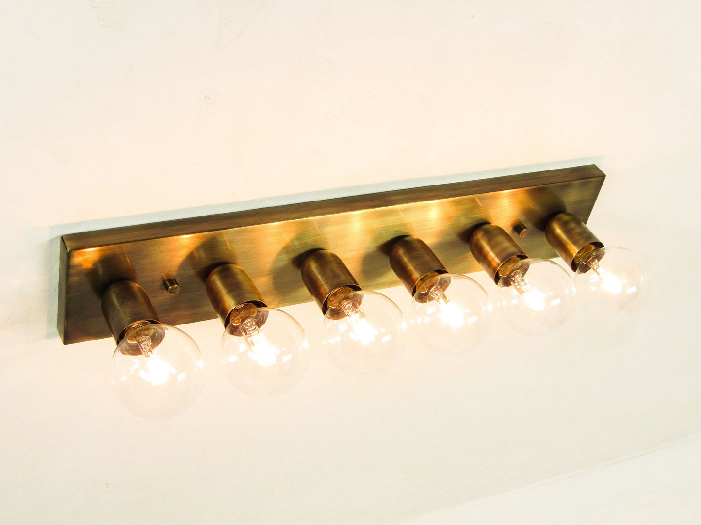 Antique bronze wall-mounted light fixture with six bulbs on a neutral background